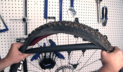The ''repaired'' tube will now have a much smaller diameter, making it a bit trickier to install than when you first put it in. Put one side of the tire onto the rim and then work the tube up and onto the rim. The tube should stretch enough that once it is onto the rim it will stay there on its own. Now install the other bead and pump up the tire to a bit less than your usual pressure. Remember that this repair is only to get you out of the bush - go around any jumps or drops that you would usually hit and ride well under your limits, stopping frequently to check the tire's pressure. This is especially true if you've repaired your front tire.