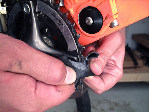 If you carry a folding knife or Leatherman in your bag you can use that to cut the tube across its diameter exactly where the puncture is located. If not, you'll need to use the teeth on your chain ring to do the job. If your bike uses a single ring and guide, lift the chain up and off of the ring. Take your time and be careful not to cut yourself as you do it. The straighter the cut, the more likely it will hold air when the time comes to test it out.
