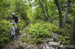 A racer blurs through a buff section of stage three. High speeds on smooth trails will quickly open up to rocky, square edged rocky trail.