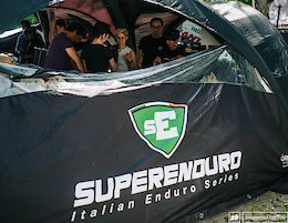 Superenduro sign on tent with eager riders.