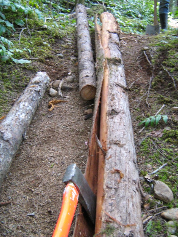 De-barking the cedar stringer. Cut a stright cut down the entire log and use the axe to peel away the bark.