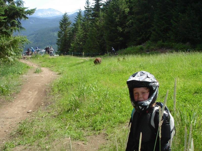 Riley standing in front of a bear in whistler.
Notice group of riders in background.
