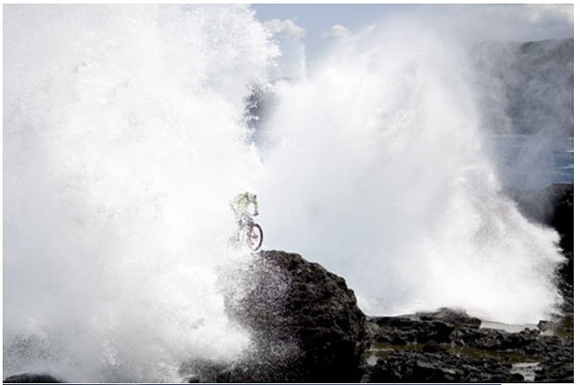 UCI number 1 ranked trials rider in Hawaii doing trials while a wave comes at him
Photo by: Erik Aeder