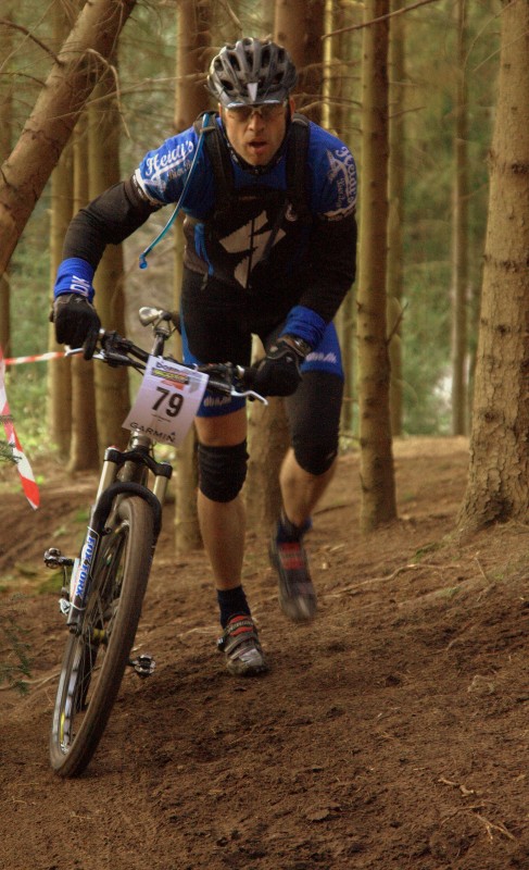rider running his bike up a technical part of the trail.