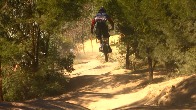 Unknown rider airing through the trees and doubling in the rythm section. Video still from filming at the NSW State Round #3.