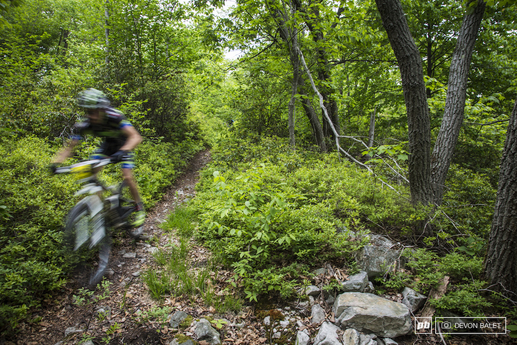 A racer blurs through a buff section of stage three. High speeds on smooth trails will quickly open up to rocky, square edged rocky trail.