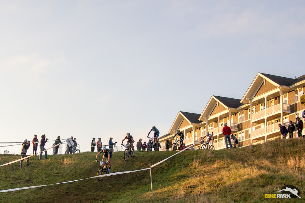 Riders plunge into the steep grassy turn after leaving the Snowshoe Village.