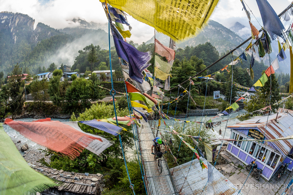Crossing a bridge covered in prayer flags in Chame, Nepal.