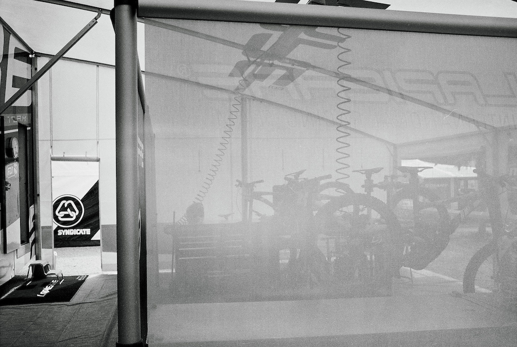 I was surprised by the silence. Bikes were ready and waiting for the riders to show up. The semi-translucent wall flattens the depth of the booth. The open door shows the neighbouring Syndicate team.
Shot with LEICA M6 / 35mm f/1.4 Summilux