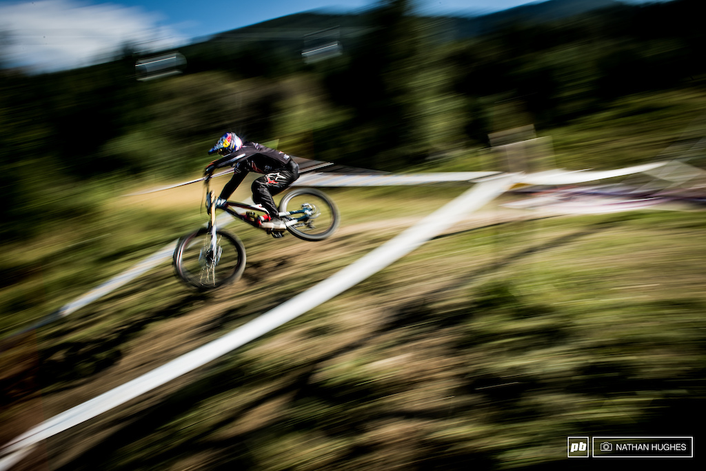 Aaron Gwin flipping the warp switch up above the woods.