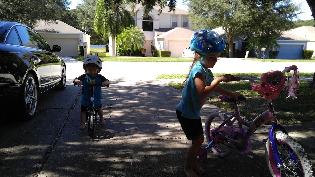 Big girl and big guy, one on the princess pedal bike, and the other on the Strider!