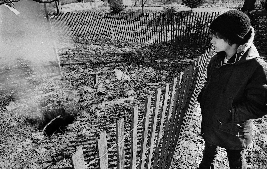 FILE - In this Feb. 14, 1981, file photo, Todd Domboski, 12, of Centralia, Pa., looks over a barricade at the hole he fell through just hours before this photo was taken in Centralia, Pa. The hole was cause by a mine fire that had been burning since 1962. After years of delay, state officials are trying to finish their demolition work in Centralia, a borough in the mountains of northeastern Pennsylvania that all but ceased to exist in the 1980s after a mine fire spread beneath homes and businesses. (AP Photo, File)