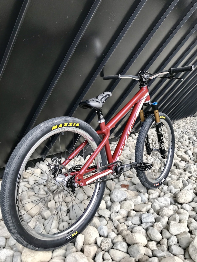 Santa Cruz Jackal. Custom Burgundy and Cream vinyl wrap, Fox 36 831 fork, Spank Spike 35 hoops laced to a Profile Elite front hub and a Profile ZCoaster rear hub. Maxxis Ikon 2.2 front, DTH 2.15 rear. Raceface Sixc 165mm carbon cranks, 28t front/10t rear sprockets with a KMC cool chain. Chromag OSX bars, Ranger stem, Contact pedals, Overture LTD seat, dolomite post, seat clamp and Wax grips. Odyssey gyro setup with a monolever brake lever, fibrax lower/primo upper cable, and an Avid BB7 road SL caliper.