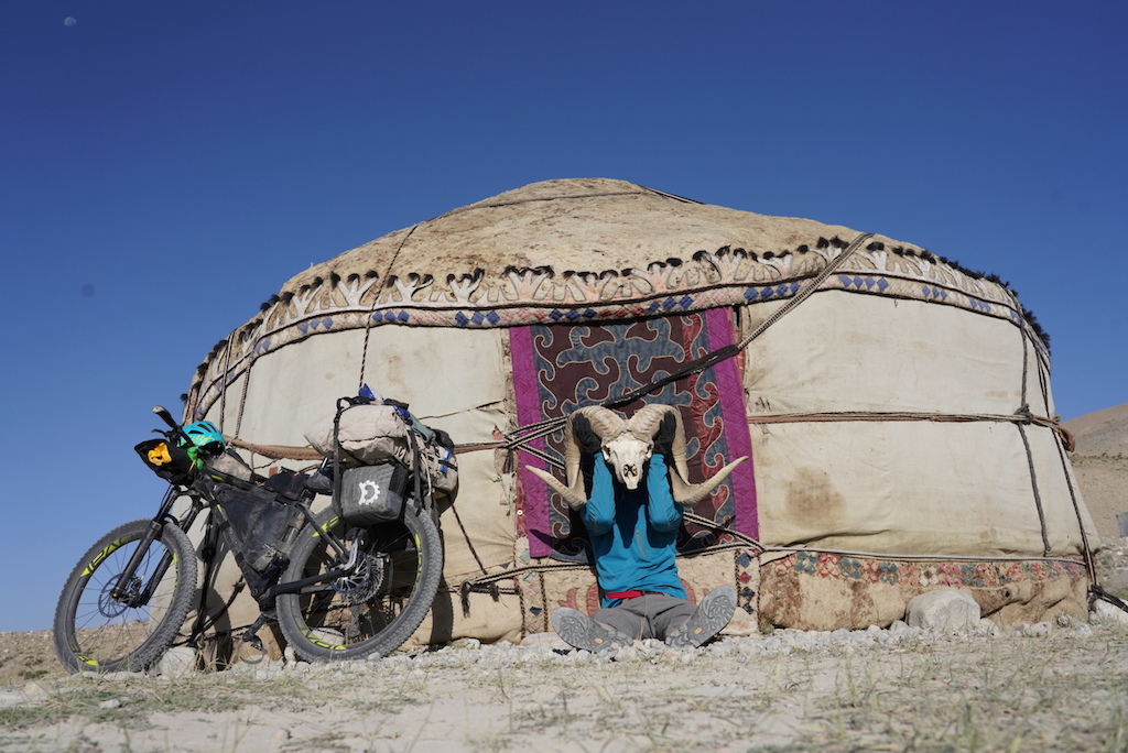 Steve Fassbinder holding up a Marco Polo sheep skull in front of an abandoned yurt in the Wakhan Corridor.
