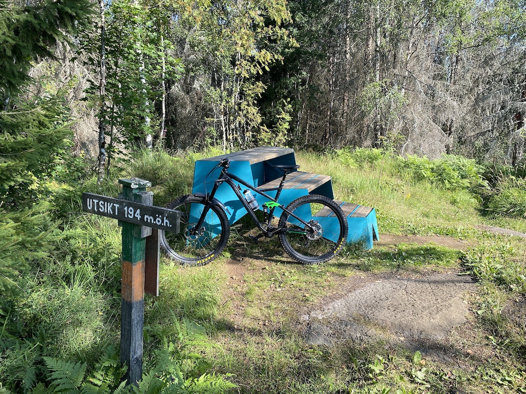 A blue gravel or trail bike leaning against blue wooden features near a trail sign.