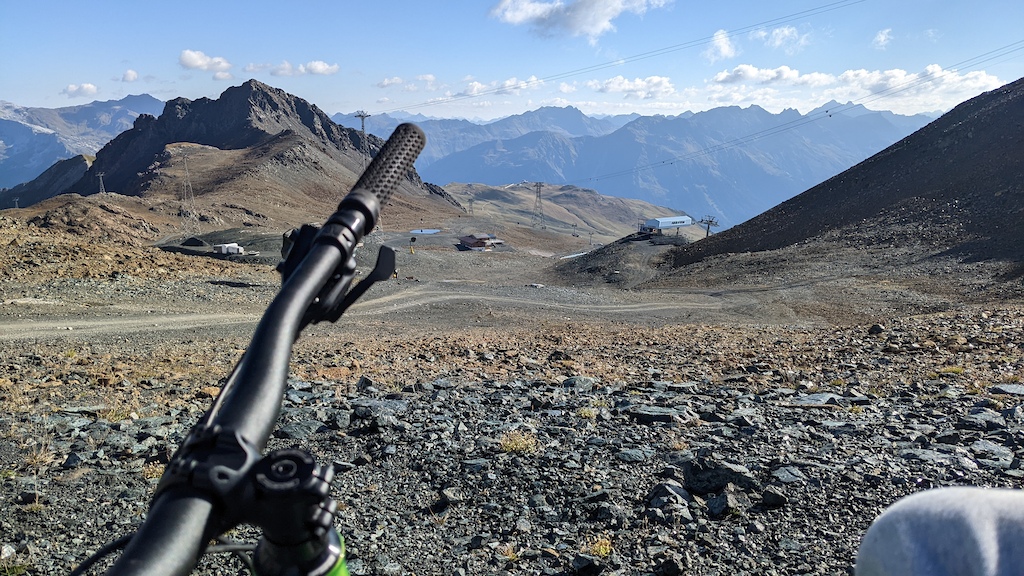 A mountain biker on a rocky alpine plateau with mountain ranges visible in the distance.
