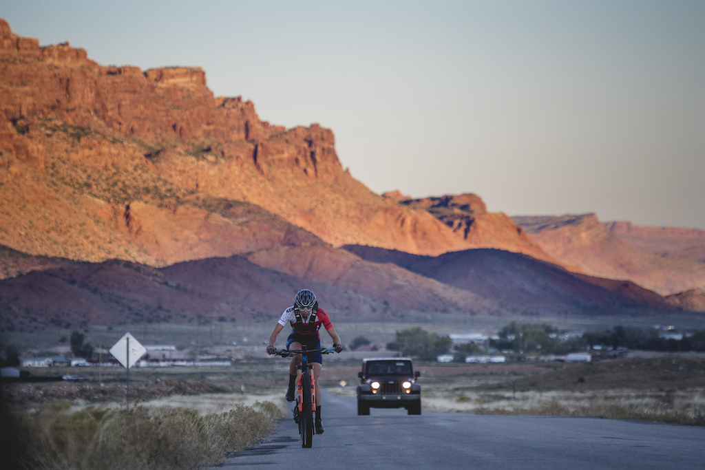 The sun begins to rise over Moab as Hannah Otto pedals south to the La Sal Loop Road, on her way to setting an FKT on "The Whole Enchilada" route, riding from town, into the La Sal Mountains and descending to the trail's end near the Colorado River, in Moab, UT.