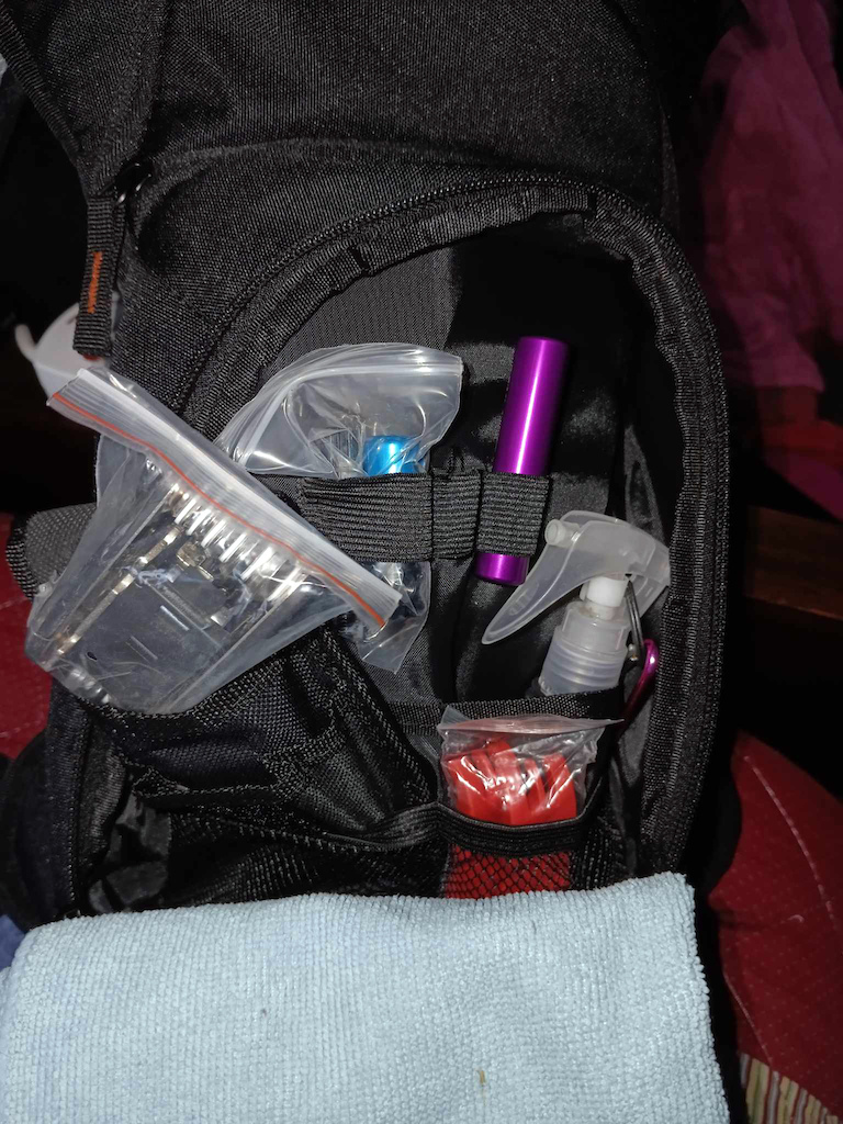 In the outermost pocket of the Hydration Backpack, I have the rubbing alcohol, a Tubeless tire patch kit, a Multi-tool, and heavy-duty, yet light [plastic] Tire Irons. a Chain Breaker tool, and lip balm. Hidden is my pocket knife.