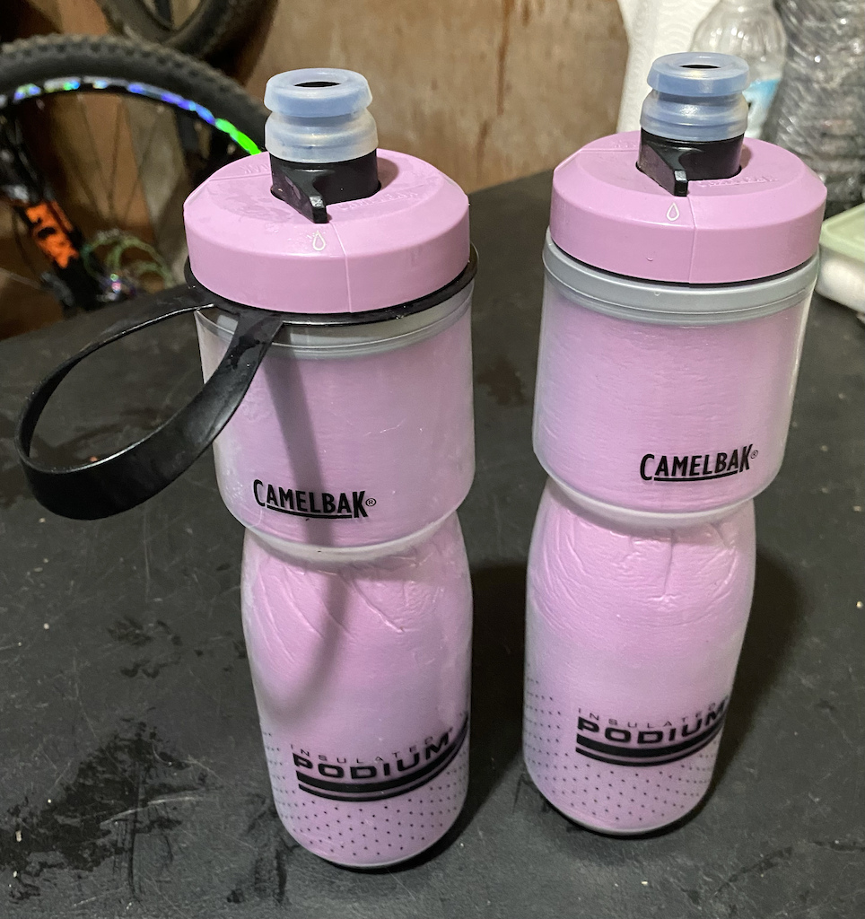 Camelback “Podium”, insulated water bottles. 

* Pros: A. The bottle is designed to be a little “squishy”, so you can “shoot” a blast of water into your mouth quickly and easily.   B. The insulation does work very well. 
* Cons: A. The open/close feature is a two-hand operation. I had one bottle “closed” in my hydration pack, and the bottle in the water bottle cage on the bike, was “open” the whole time. 
B. This bottle is VERY SLIPPERY. Almost every time that I grabbed it out of water bottle cage and tried to drink from it, then getting it back into the water bottle cage was a crap shoot. As it was sliding out of my grasp in both directions.  I added the strap from a previous water bottle, which helped immensely.