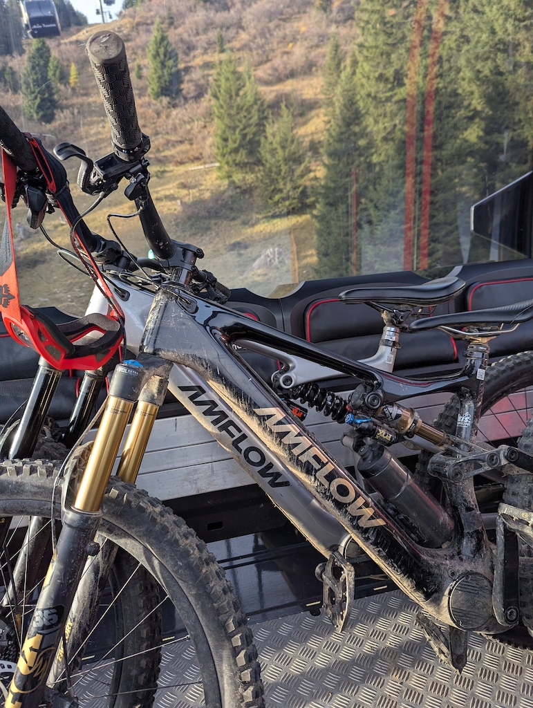 A mountain bike propped on a cable car platform with forested mountainside in the background.