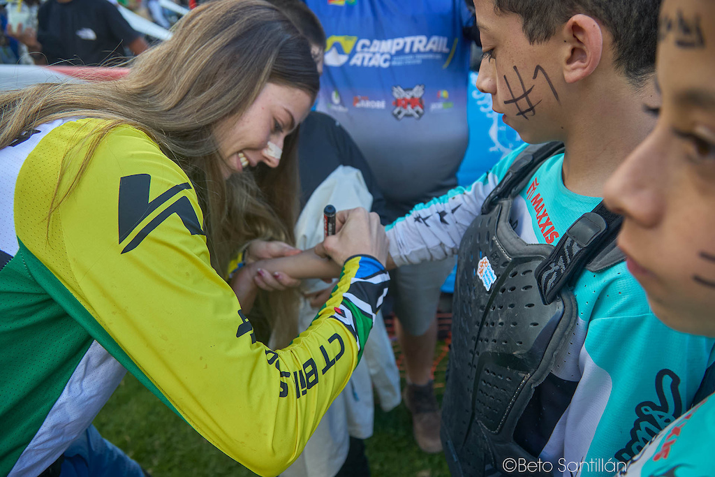 Larissa Luz  — This is what it is truly all about. The race is over, the adrenaline has settled, and Brazil's brightest star takes a quiet moment to sign the arm of a young fan whose painted face tells the whole story — he came here to see his hero, and his hero showed up for him completely. No rush, no distance, just a genuine smile and a marker meeting skin. These are the moments that plant seeds of dreams in young hearts. Today's fan is tomorrow's champion — and Larissa knows it better than anyone. Obrigada, Larissa.