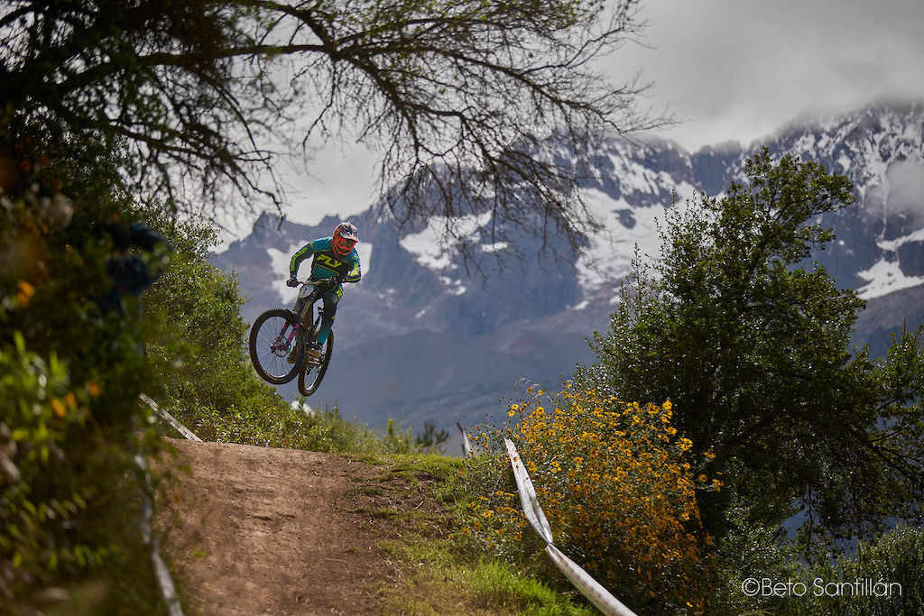 Sergio Guevara  — Suspended between earth and sky, with the mighty glaciers of Apu Chicón watching over every second of his flight. This is not just a photograph — this is a painting. Wildflowers below, snow-capped peaks above, and one fearless rider suspended perfectly in the sacred space between both worlds. Santísimo DH 12 does not just test your speed and your courage — it frames you against the most breathtaking canvas on the continent. And Sergio wore it like a champion.