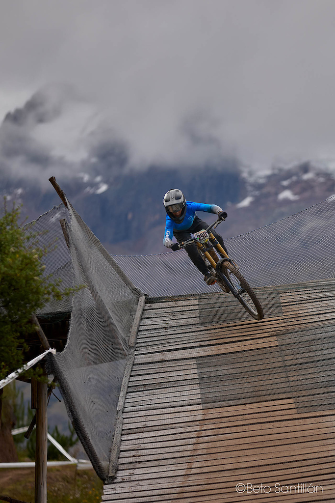 Sky, snow and pure speed. Franco Vargas launches off the iconic Juanito Bridge at Santísimo Downhill 12 in Chicón, Urubamba - Cusco, with the dramatic snow capped peaks of the Sacred Valley disappearing into brooding Andean storm clouds directly behind him. It is one of the most breathtaking backdrops in all of South American downhill racing and Franco owns every inch of it — wheels in the air, body compact and controlled, fully committed to the line that leads him deeper into the heart of this legendary mountain. There are race tracks and then there is Chicón. There are riders and then there is this moment.