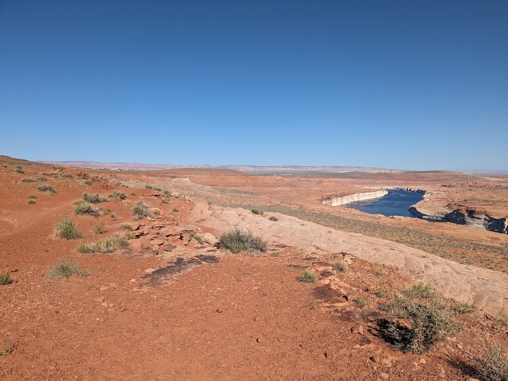 Open desert terrain with sparse vegetation and a distant river bend below.