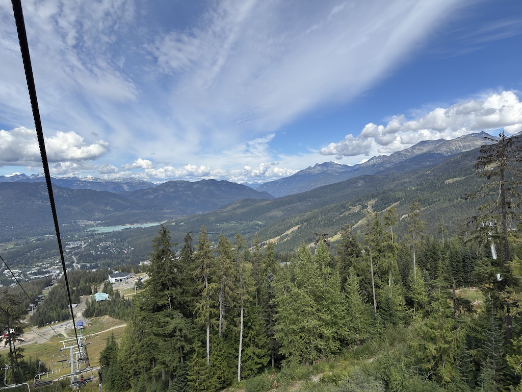 Forest and alpine terrain with expansive valley views and mountain ranges in distance.