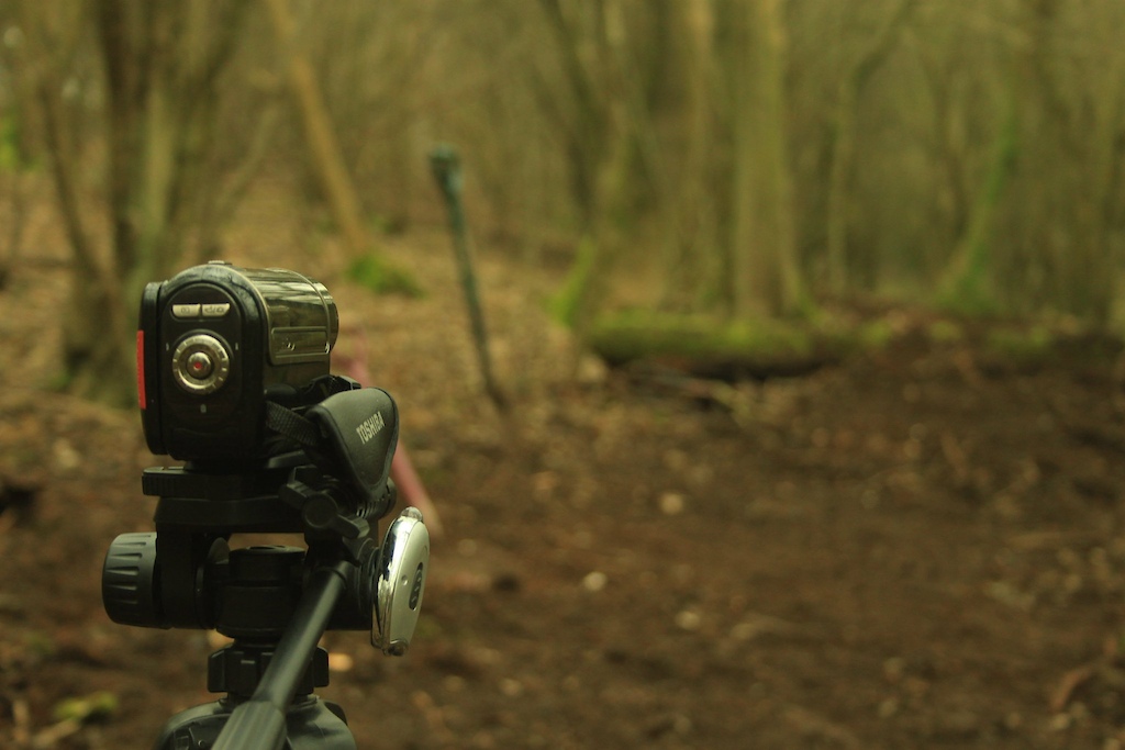 A photo of George's video camera. Behind that is, with the mossy covered logs, is the landing. The first jump will the a 17ft gap and 3-4ft tall. The second will be a 17ft gap again, but 6ft tall. The third will be a 45° hip about 6ft and the gap will be about 15-20ft. Photography by George Power.