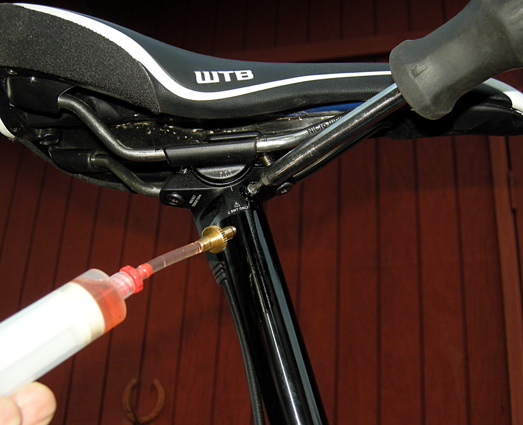 Give the remote syringe a strong push and then unscrew the seatpost syringe and screw in the proper plug. It has an O-ring, so the plug only needs to be tightened to a snug fit. A little fluid will escape.