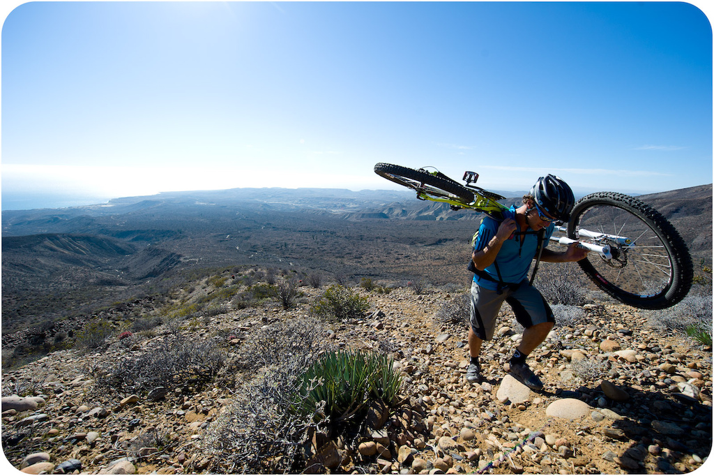 Richie Schley carries his bike up the long trail to the top of the mesa at Punta San Carlos.