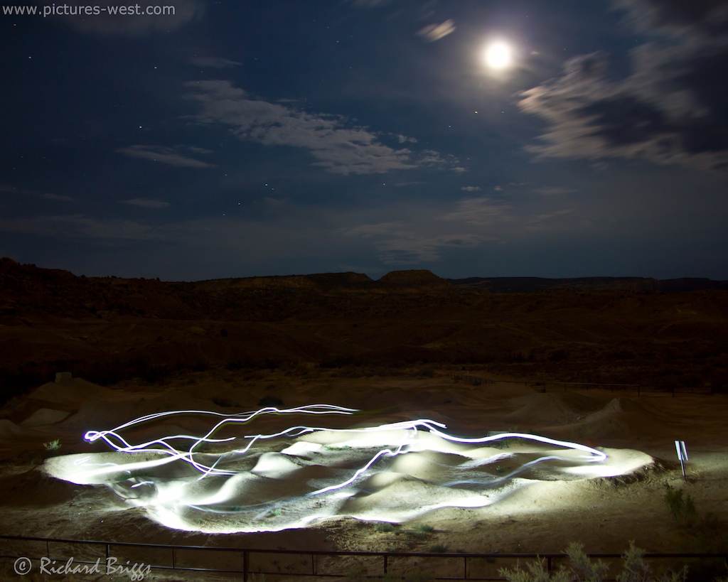 A timed exposure of Kyle Fissel riding the Lunch Loop Pump Track at night with lights on.
