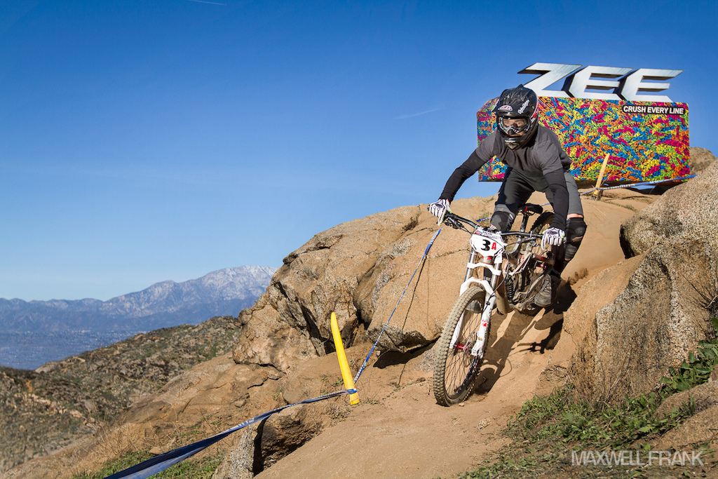 Waylon Smith taking the first drop by the Shimano Zee advertisement with the snow capped mounting in the background.