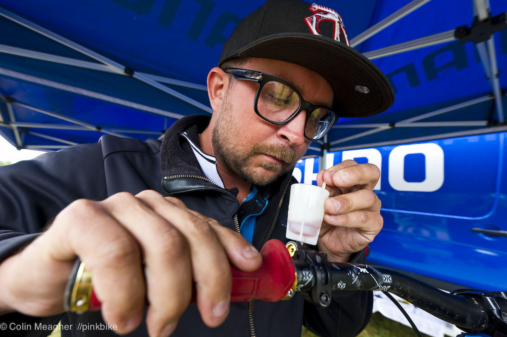 Shimano Tech rep Ryan Gaul plumbing the depths of Luke Strobel's Saint Brakes. "the little plunger I'm using kind of works like a toilet plunger: I squeeze the lever, and then use the little plunger to pull out any stray air bubbles."