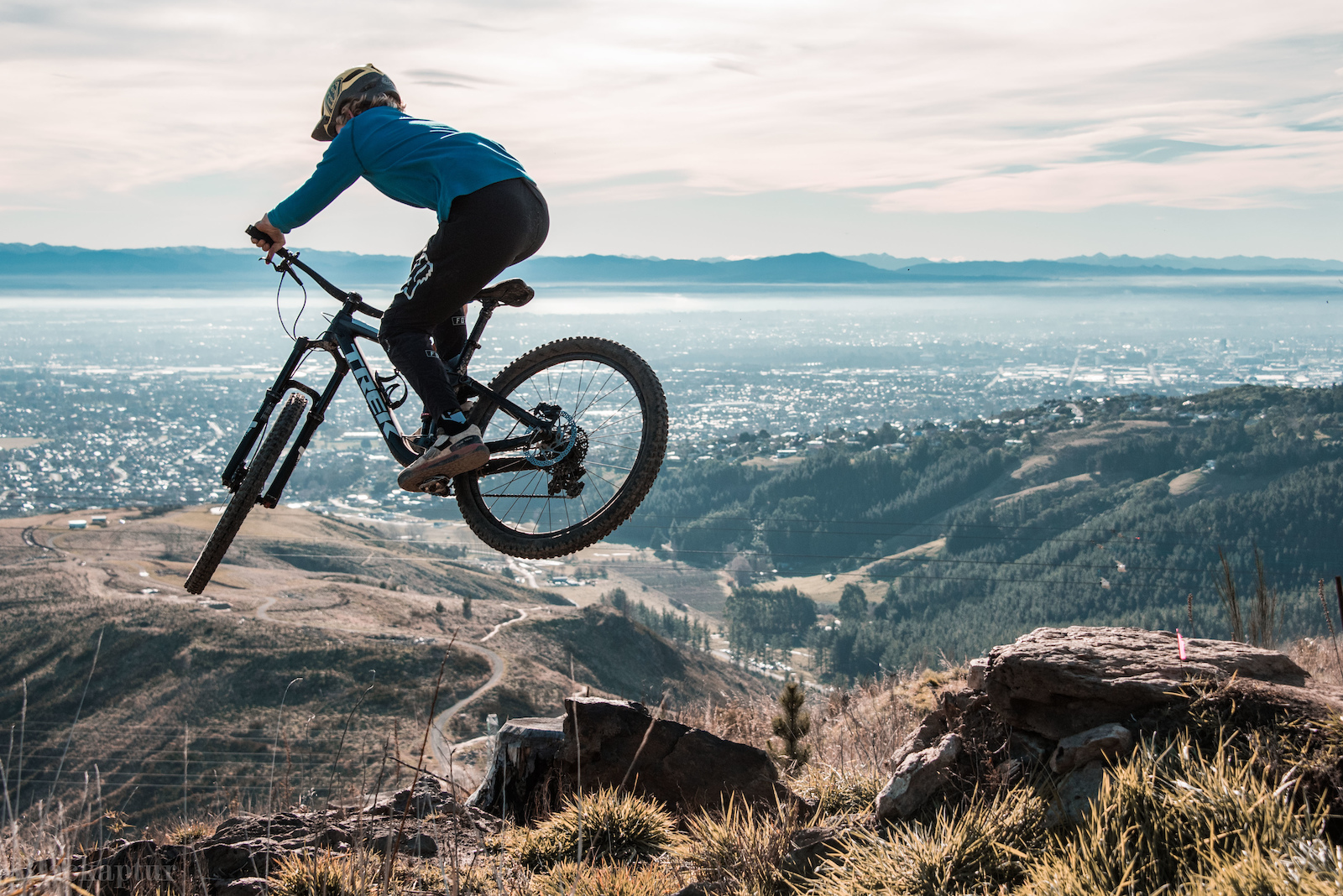 Lui steezes his way over small rock drop/step down on the amazing Throw the Goat trail at the Christchurch Adventure Park with views over Christchurch City and the Mountains in the distance...
