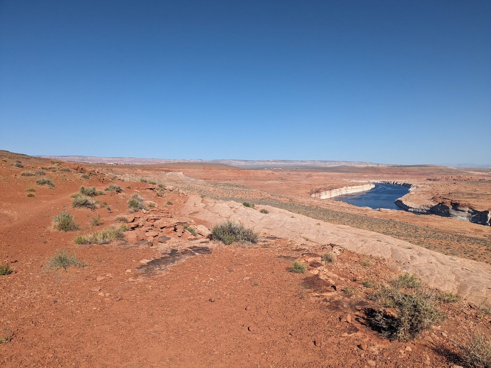 Open desert terrain with sparse vegetation and a distant river bend below.